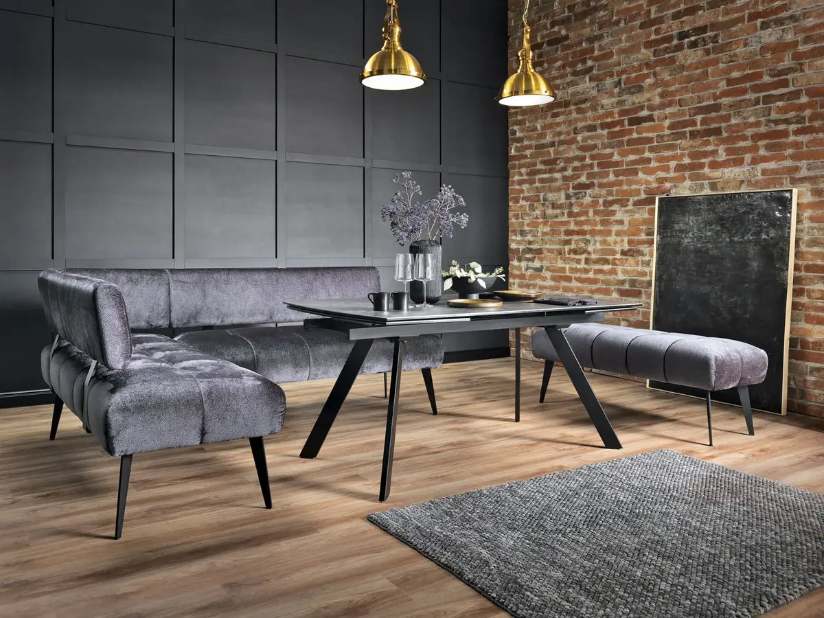 Modern dining room with gray sofa, table, and chairs against a brick wall.