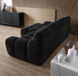 Black sofa in a modern living room with wooden floor and decorative vases.