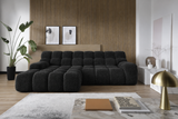 Modern living room with a large black sofa, gold lamp, and decorative items.