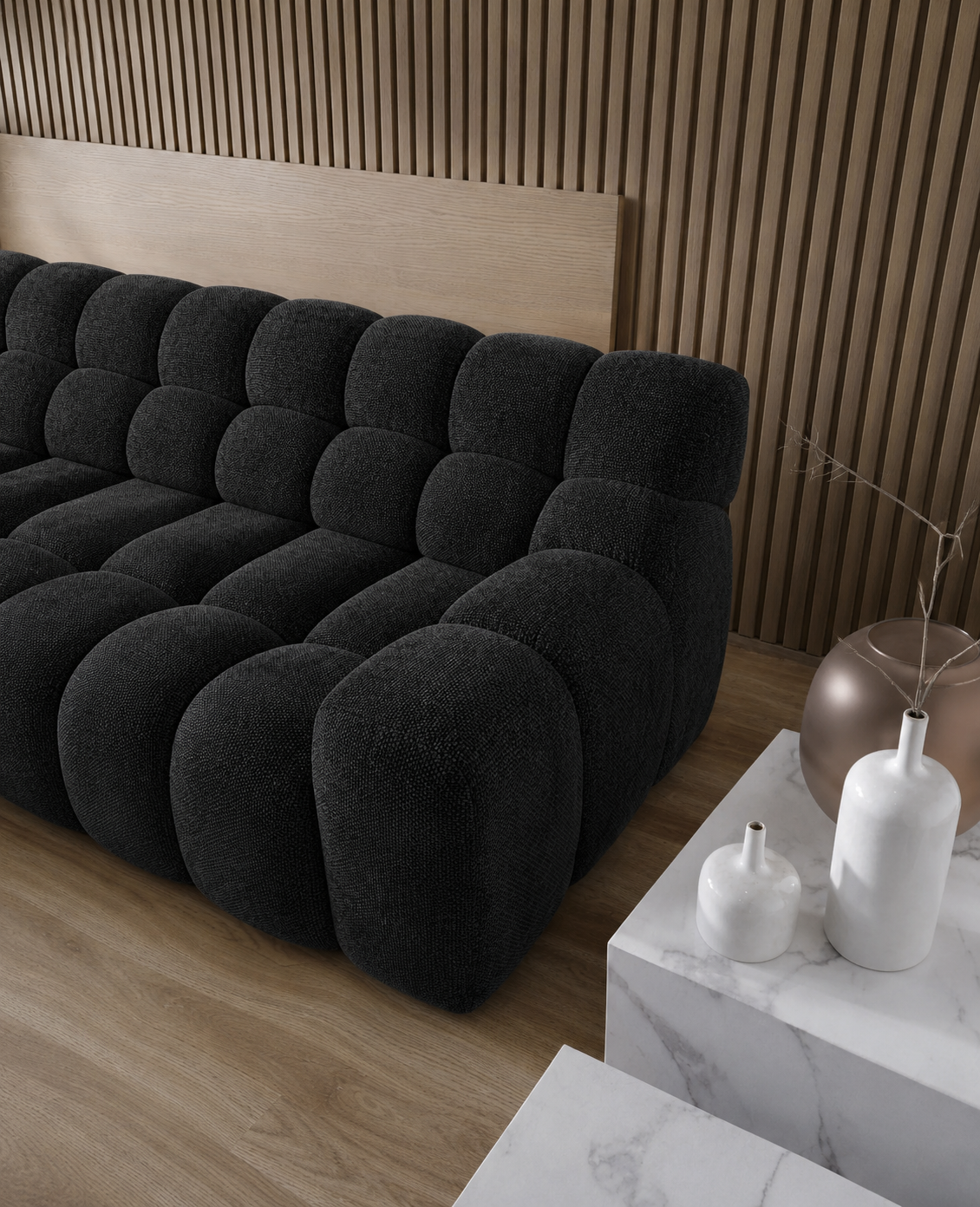 Black tufted sofa in a room with wooden walls and a marble side table.