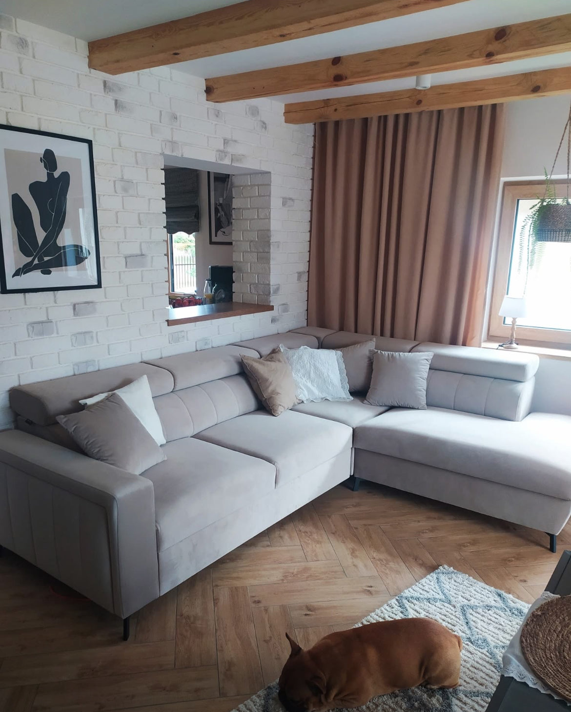 Living room with a gray corner sofa Bloom, wooden floor, and decorative elements.