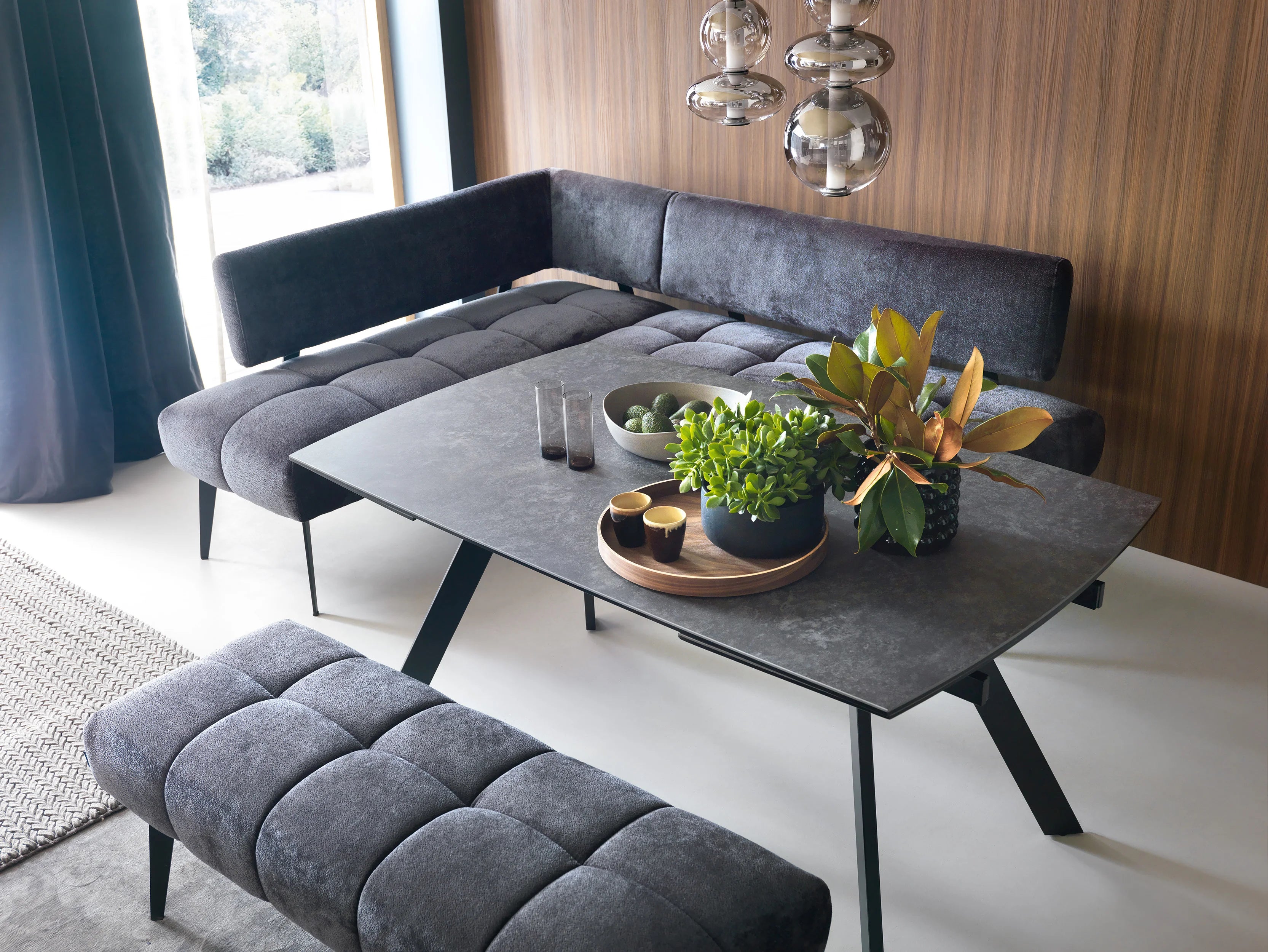 Modern living room with gray sectional Milo-kitchen corner sofa, coffee table, and decorative plants.